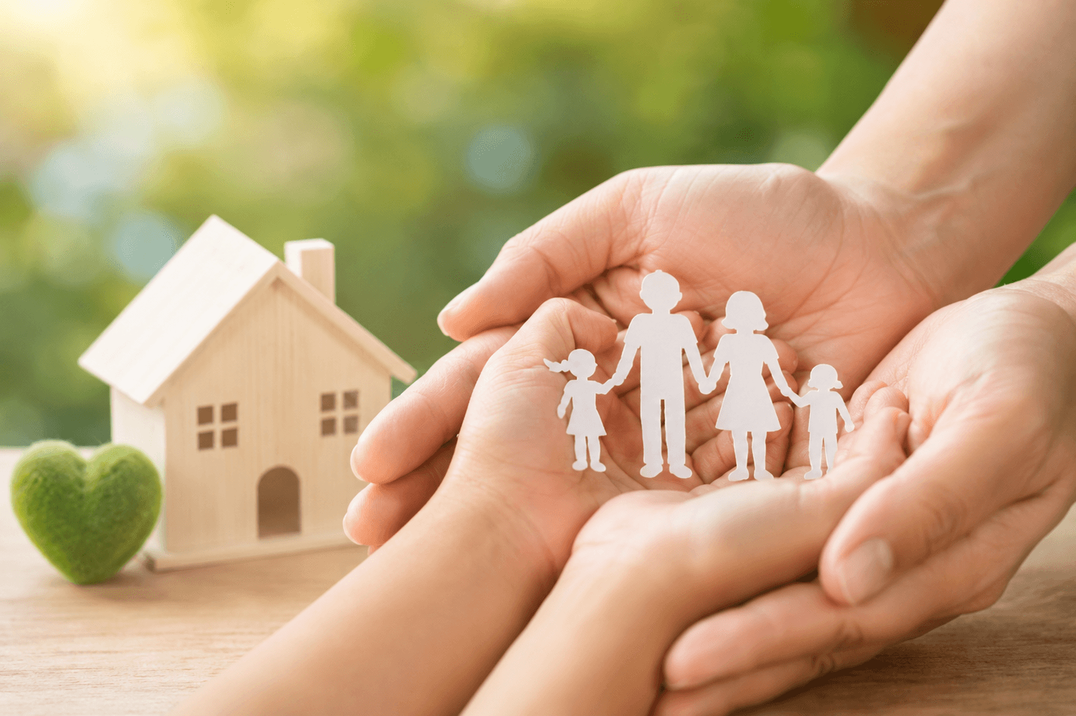 Cupped hands protecting a paper family beside a home